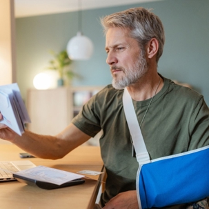 Man in sling receiving a denied workers' compensation claim