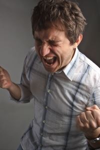 Photo of a man yelling loudly with his fists clenched and eyes closed