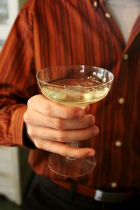 Person wearing a red blouse holding an alcoholic beverage