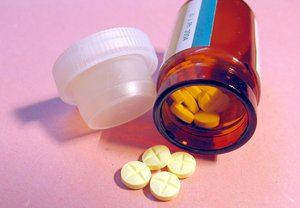 photo of a amber colored bottle of pills knocked over with 4 yellow colored pills on the table